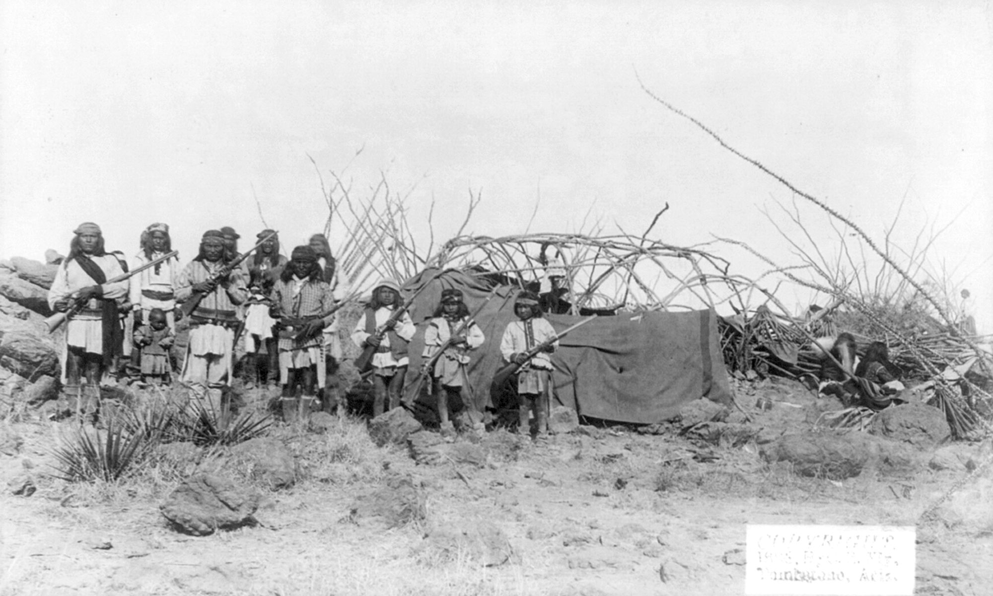 C.S. Fly's photo of the well-armed Chiricahuan men captioned, "Scene in Geronimo's camp before surrender to General Crook, March 27, 1886: Group in Natches' camp; boys with rifles."