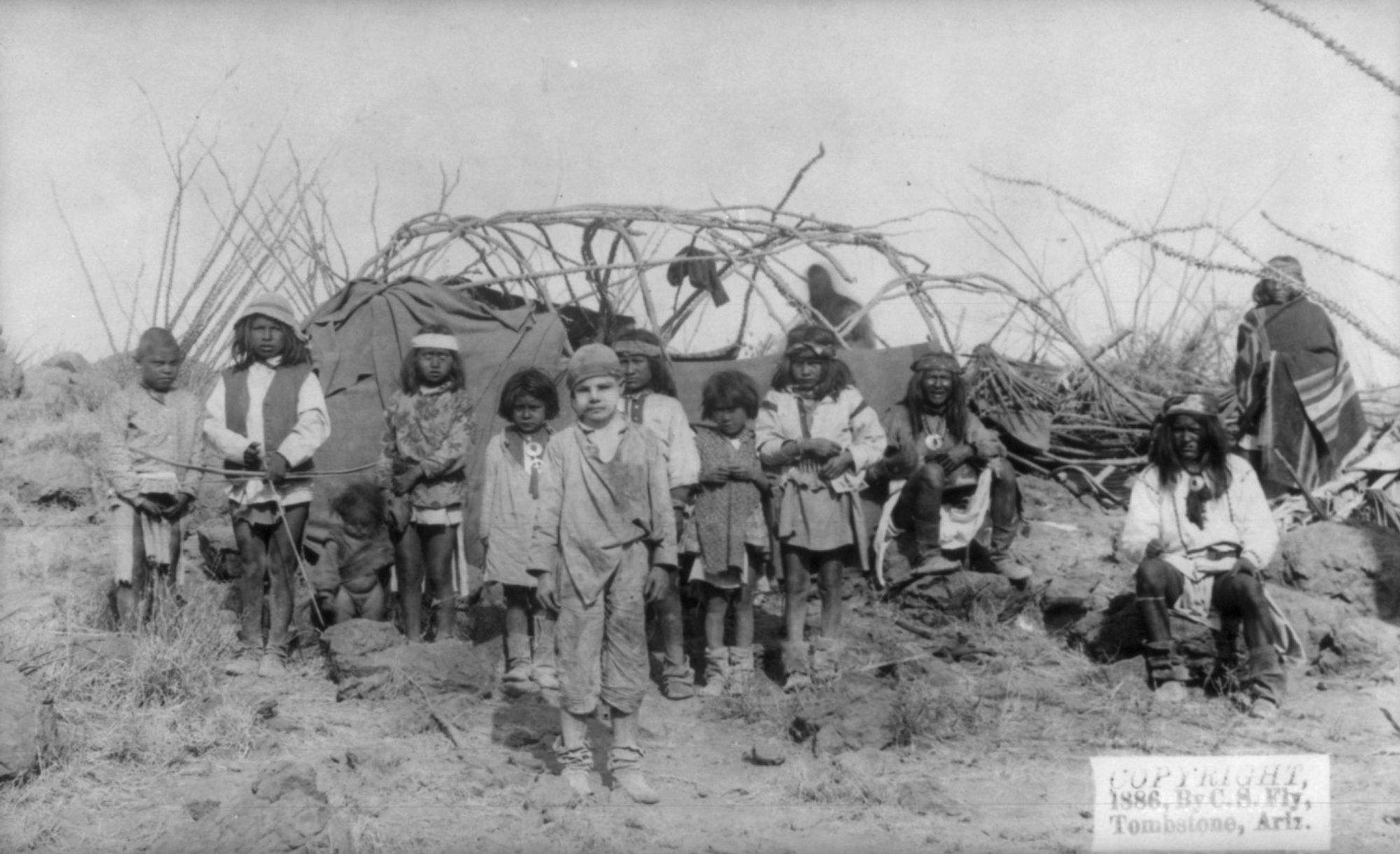 Women and children in Geronimo's camp during late March 1886. Shown in the photo is 11-year old Jimmy McKinn, who was abducted by the band. He had been kidnapped in September 1885, and "fiercely resisted" returning to his parents despite the fact that the same Apaches had killed his brother. It was reported in more than one newspaper that he had been "fully Indianized."