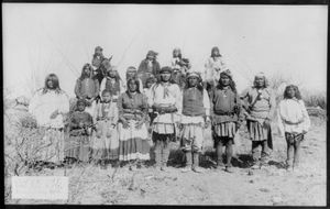 Captioned: ""Scene in Geronimo's camp...before surrender to General Crook, March 27, 1886: group of 18 men, women and children." Photo by C. S. Fly